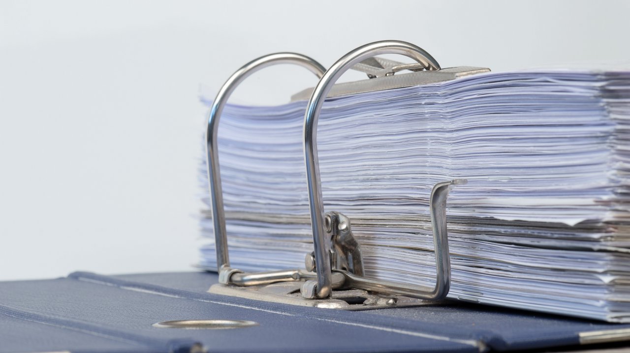 Das Bild zeigt einen aufgeklappten Aktenordner mit Schriftstücken
