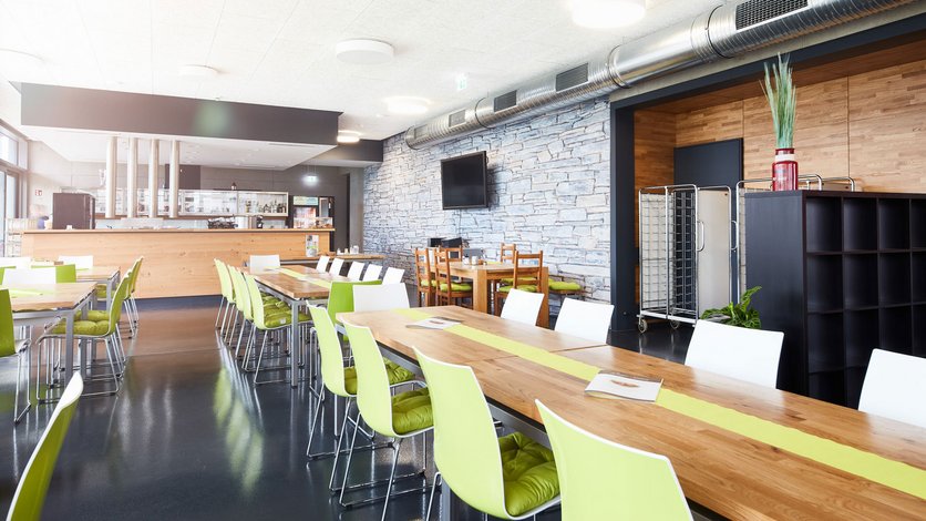 Casino mit Tischen und Stühlen und Blick auf die Selbstbedienungstheke