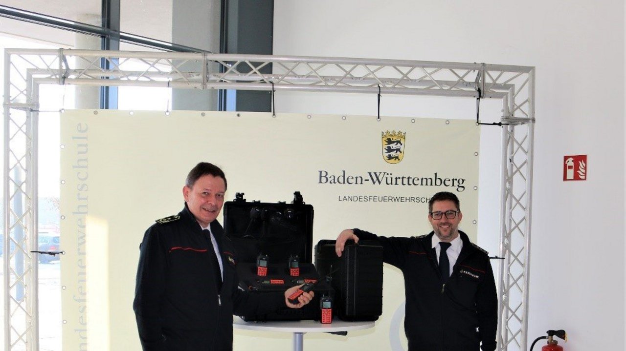 Schulleiter Frieder Lieb (links) und Andreas Schmidt vom Innenministerium bei der Übergabe der 60 Handsprechfunkgeräte an die Landesfeuerwehrschule.