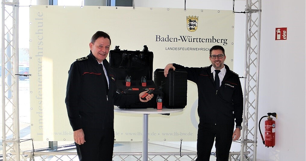 Schulleiter Frieder Lieb (links) und Andreas Schmidt vom Innenministerium bei der Übergabe der 60 Handsprechfunkgeräte an die Landesfeuerwehrschule.