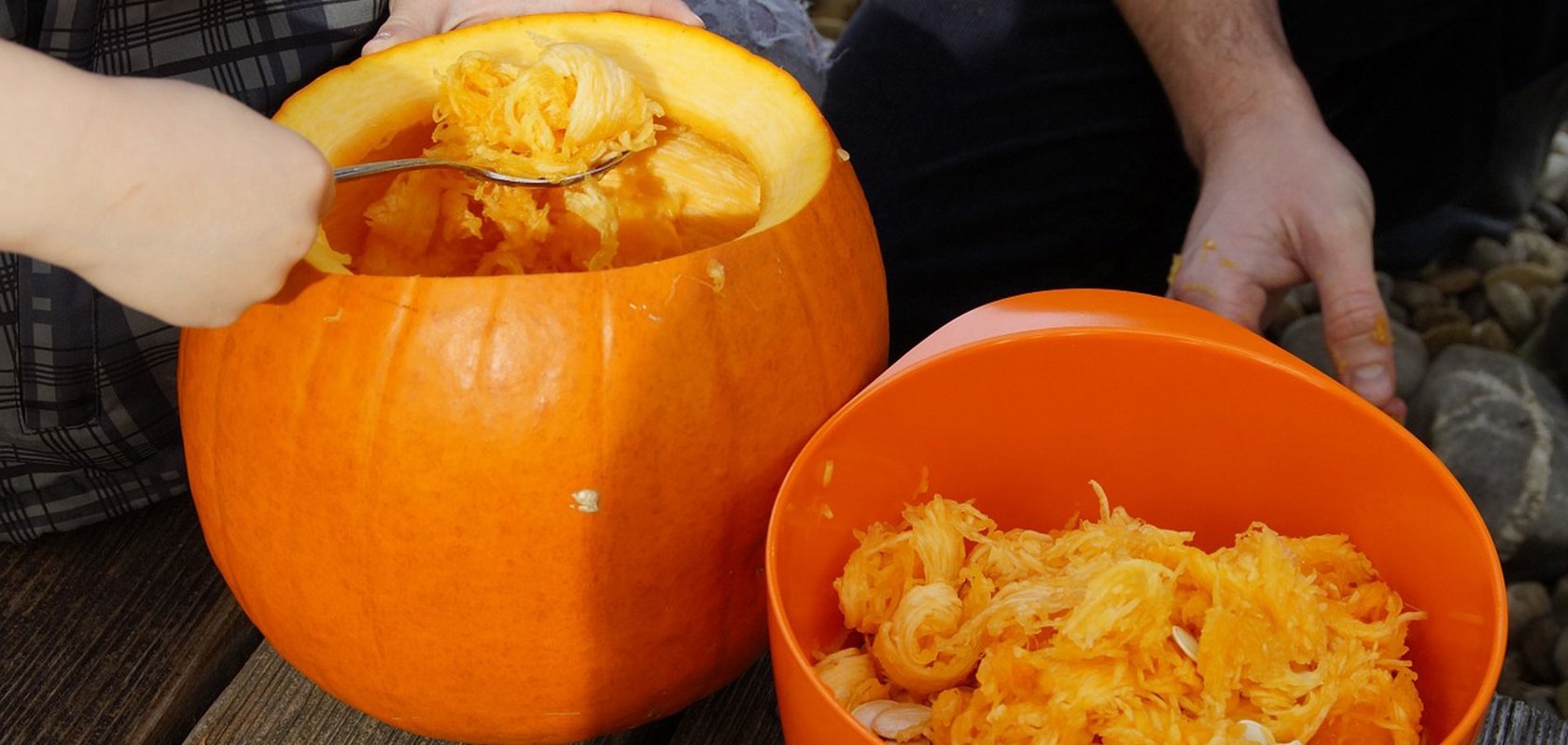 Kinderhände die mit einem Löffel einen Kürbis aushöhlen