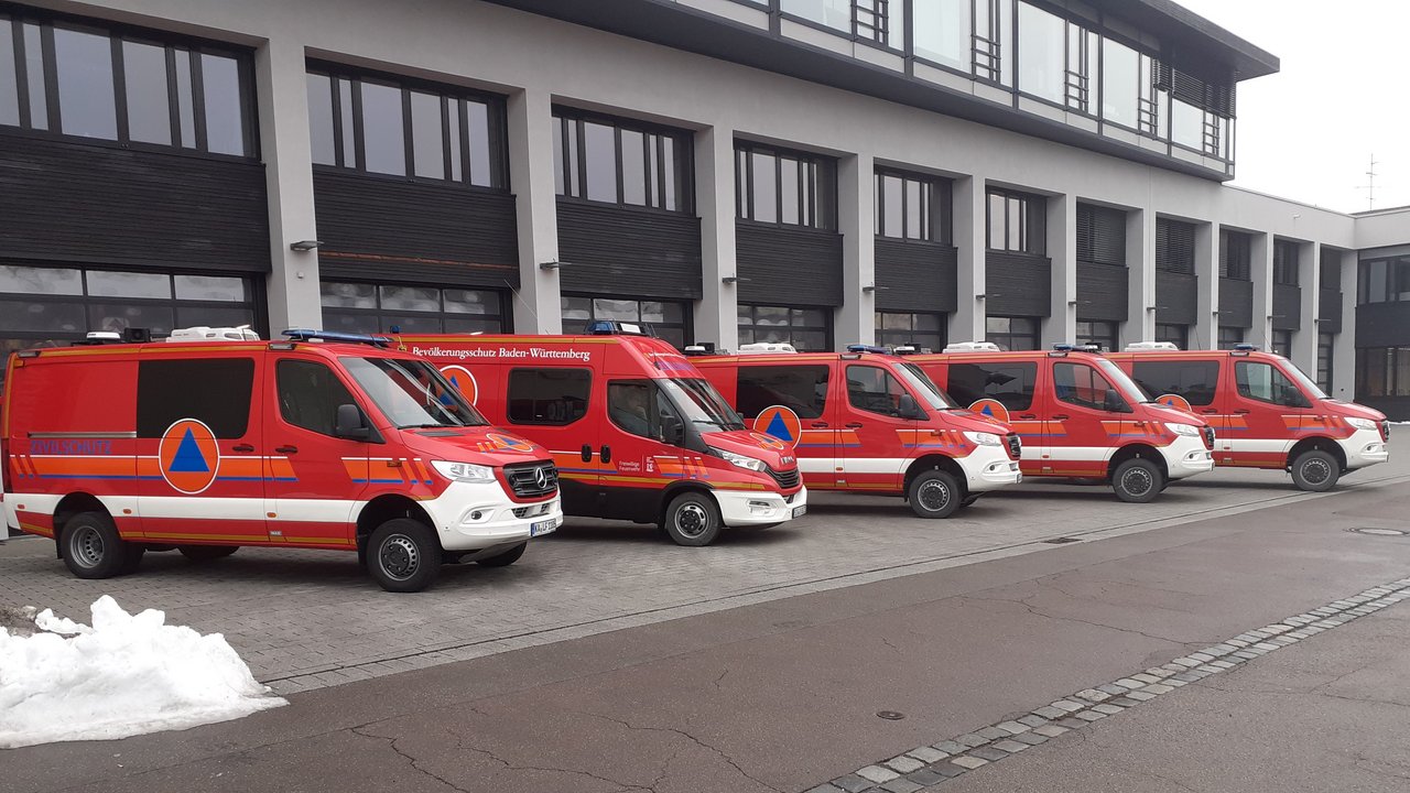 Das Foto zeigt 5 Feuerwehrfahrzeuge des Strahlensprühtrupps vor einer Großen Halle