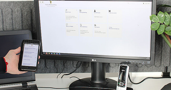 Computerbildschirm der die Anmeldemaske des Bildungsportal zeigt und daneben ein Handy mit der gleichen Anmeldemaske