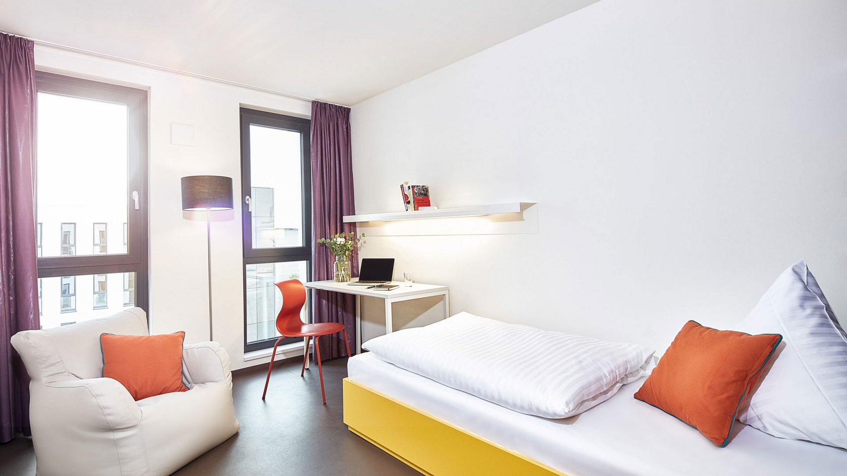 Zimmer mit Bett, Sessel und einer kleinen Schreibecke