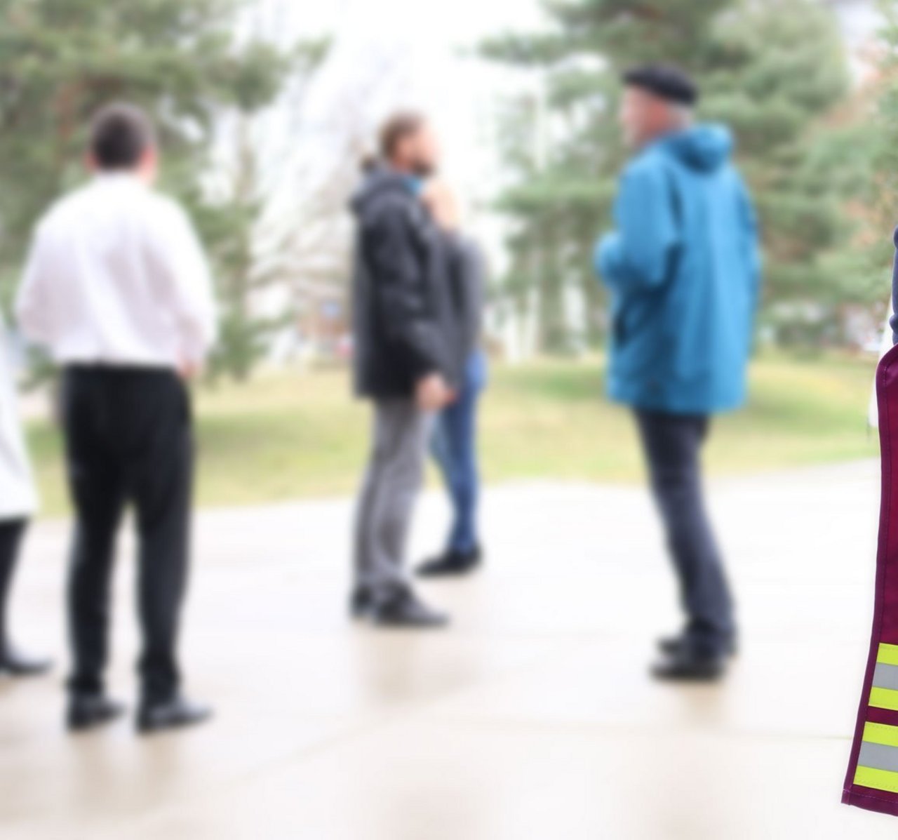 Person mit PSNV Weste, im Hintergrund eine kleine Gruppe ziviler Personen