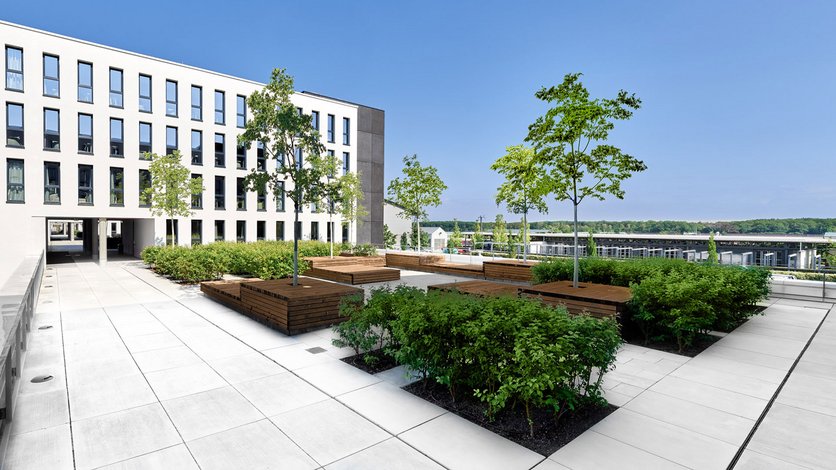 Begrünte Dachterrasse zwischen den Wohntürmen mit Sitzmöglichkeiten aus Holz