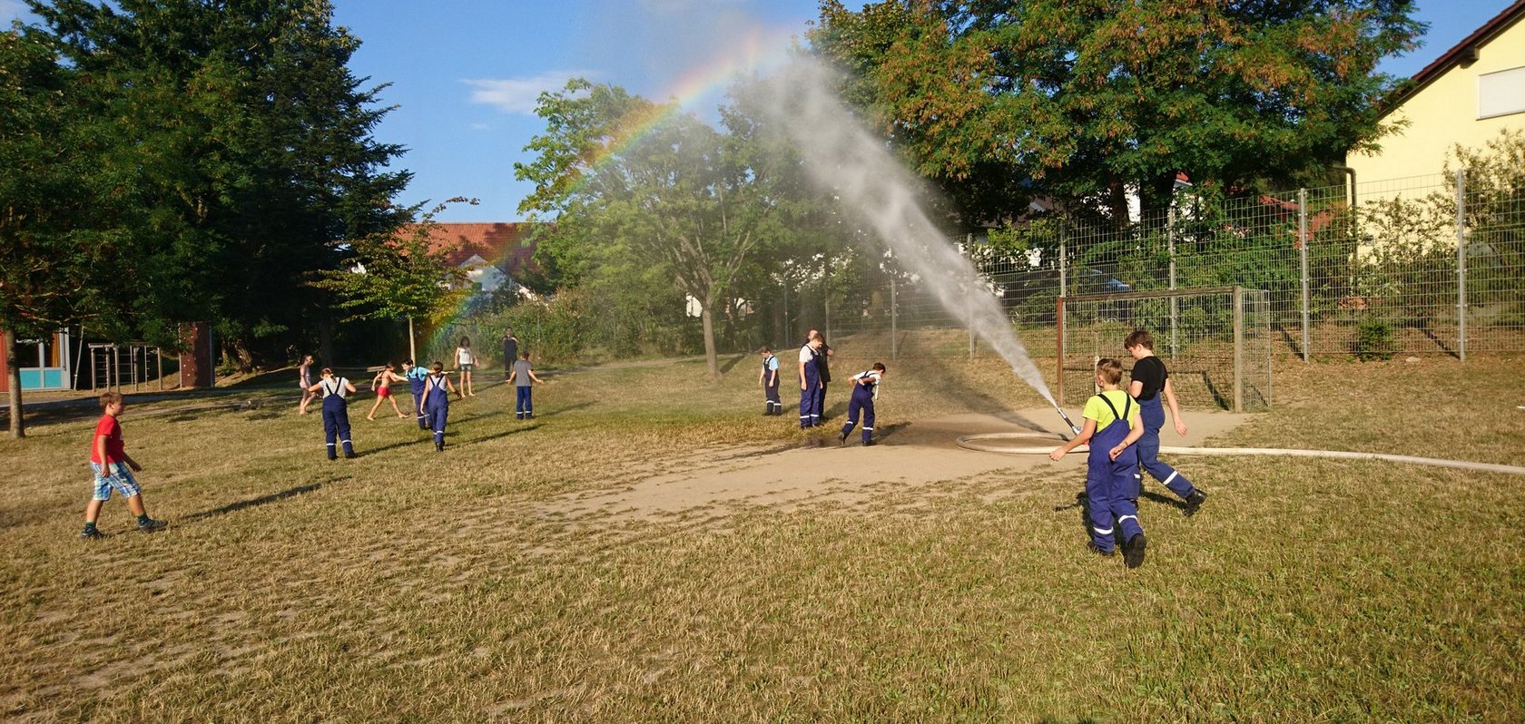 Kindergruppe auf einem Fussbaldfeld bei Wasserspielen