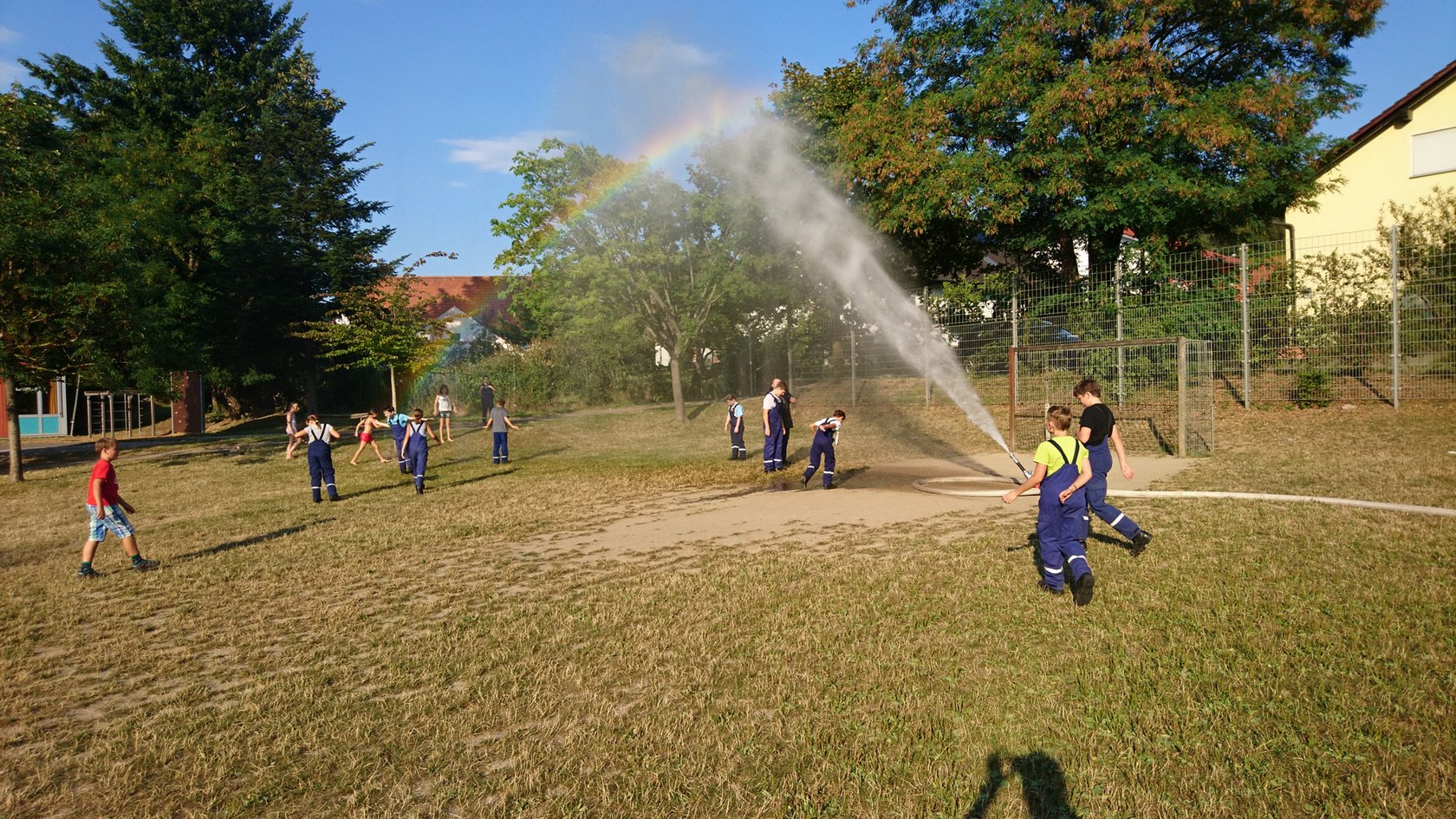Kindergruppe auf einem Fussbaldfeld bei Wasserspielen