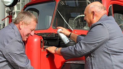 Zwei ältere Männer bei der Pflege eines historischen Feuerwehrfahrzeug
