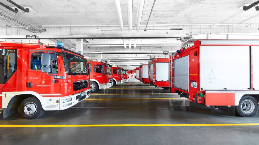 Blick in eine der Fahrzeughallen mit verschiedenen Lösch- und Einsatzfahrzeugen, geparkt in zwei Reihen hintereinander