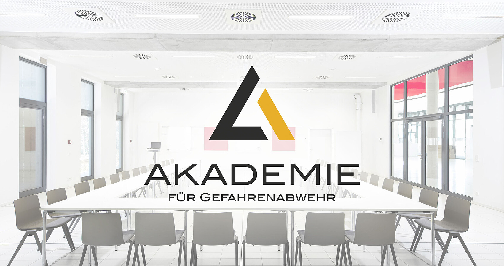 In U-Form bestuhlter Seminarraum der Akademie mit überblendetem Logo