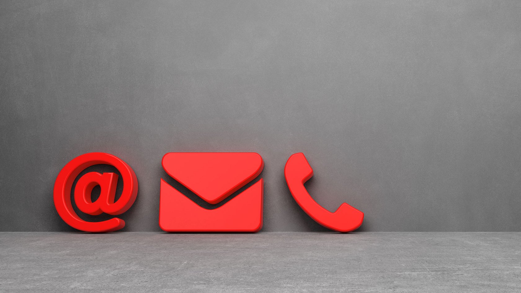 Ein rotes @-Zeichen, ein Briefumschlag und ein Telefonhörer als Symbol vor einer grauen Wand