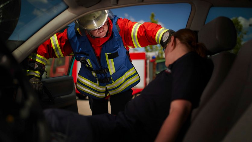 Übung an einem KFZ. Einsatzfrakt beugt sich ins Fahrzeug und spricht mit dem "Verletzten".