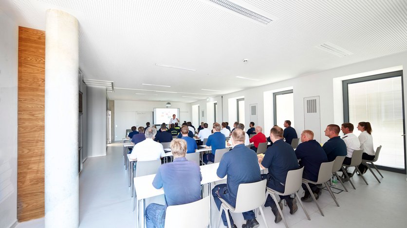 Blick in einen mit rund 36 Personen besetzten Lernraum, im Hintergrund der Referent am Multifunktionsboard 